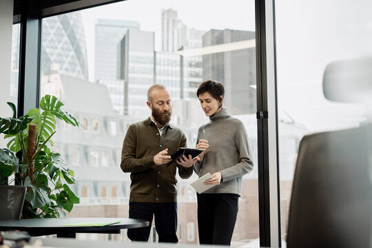 Businessman discussing with colleague through tablet PC in office