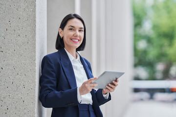 Business woman using a tablet outdoors in a city setting