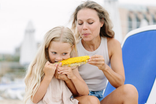Mother and daughter enjoying corn cob at beach