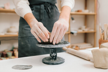 Process of creating ceramic products. Female potter hands shows ceramic bowl ready for firing in a kiln.