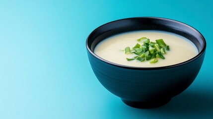 Minimalist Close Up of Chawanmushi in Black Bowl with Scallions on Blue Background