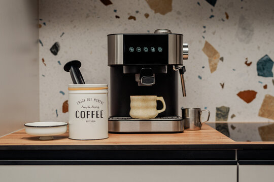 Modern coffee corner: espresso machine, cup, and milk jug.
