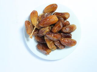 plate of fresh, glossy dates stacked on a white dish isolated on white background