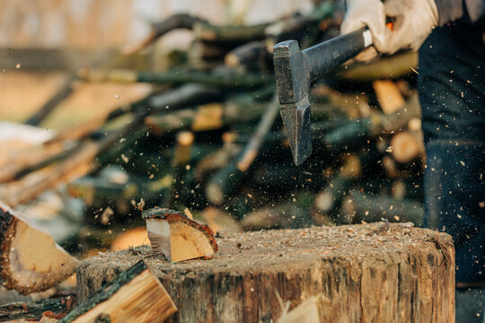 Man chopping wood with an axe on a stump in a European village