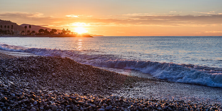 Sunrise over the Mediterranean Sea at a pebble beach in Menton, C�te d'Azur, France