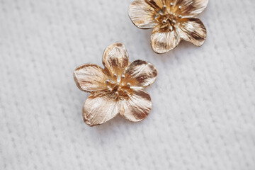 Metallic flower ornaments on a textured white fabric background