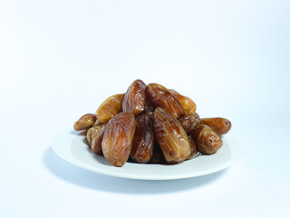 plate of fresh, glossy dates stacked on a white dish isolated on white background