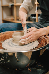 Artisan sculpts a pottery plate on the spinning wheel. Craftswoman is molding porcelain dish in the pottery studio.