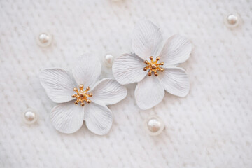 Fototapeta premium Elegant white flower accessories with golden accents and pearls on fabric