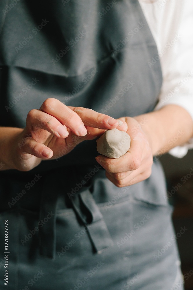 Poster potter holds a piece of wet clay in their hands, molds it into form. process of creating ceramic pro