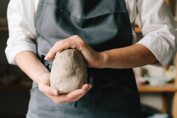 Potter holds a piece of wet clay in their hands, molds it into form. Process of creating ceramic...