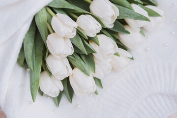 White tulips arranged artfully on a white fabric background