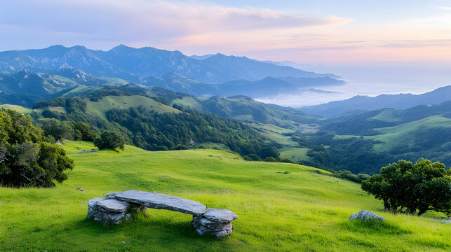 A stone bench rests on a lush, green field with foggy mountain views