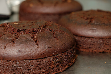 Chocolate cake layers cooling on a kitchen counter, ready for decoration and assembly at a bustling bakery during the afternoon