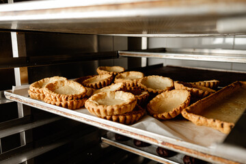 Delicious tart shells cooling on shelves in a bustling bakery during the early morning hours filled...