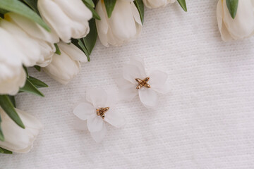 Delicate white flowers with gold accents beside fresh tulips on a soft surface