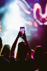 Hand with a phone records live music festival. People taking photographs with smart phone.