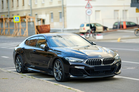 Minsk, Belarus. Aug 29, 2024. BMW M850 black sedan parked on roadside of busy city street, sleek design, luxury appeal, and high-performance engineering in an urban setting. Front view on headlights.