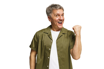 Older man celebrating victory with a joyful expression and raised fist in a light background