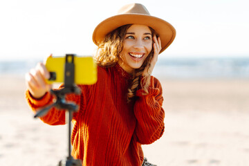 Young woman using smartphone with stabiliser  to create video content for social media on a sunny...
