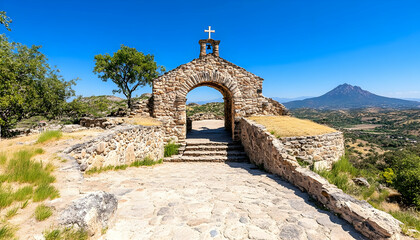 Obraz premium Stone chapel sits atop mountain with a cross on blue sky for religion, tourism