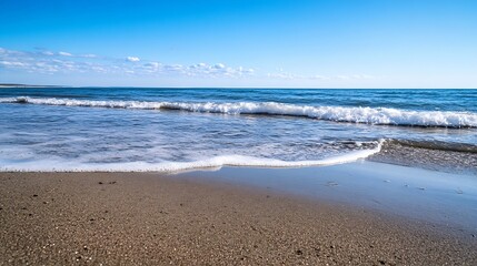 Serene view of the coastline with gentle waves rolling onto a sandy beach under a clear blue sky : Generative AI