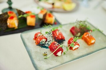 A dish with various rolls of sweet pepper sauce and a vegetable side dish. The serving is colorful and mouthwatering, with a combination of textures and flavors.