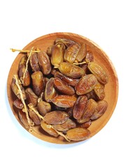 Pile of sweet dates on a wooden plate isolated on white background. Dried date fruit or dates, ramadan food