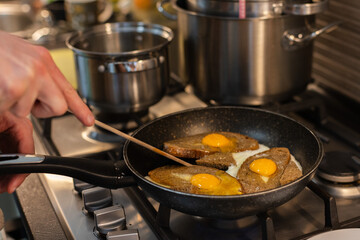 Man cooking fried eggs with croutons for breakfast.