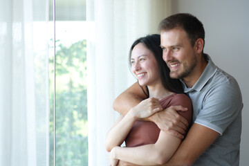 Happy interracial couple hugging and looking away