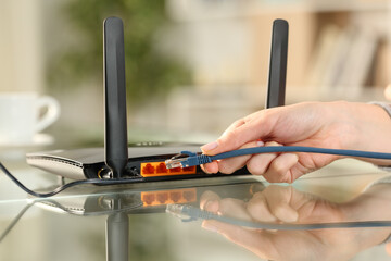 Woman hand plugging network cable to a modem at home
