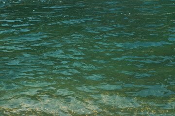 Blue water with ripples on the surface. Defocus blurred transparent blue colored clear calm water surface texture with splashes and bubbles. Water waves with shining pattern texture background.
