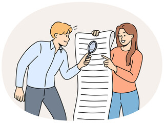 Man and woman are studying large business document using magnifying glass to look for hidden information in legal documents. Business people analyze and check data before signing contract