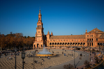 Fototapeta premium Crowds of tourists walk and explore the iconic Plaza de España historic square in Seville Spain on a bright autumn day