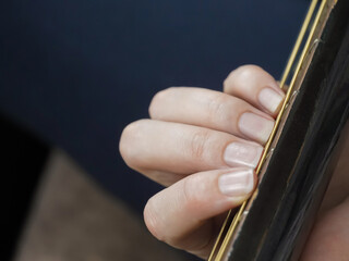Close-up view of a musician's hand gracefully resting on the strings of a guitar, capturing the...
