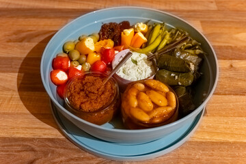 Colorful Mediterranean mezze platter showcasing fresh vegetables, dips, and stuffed leaves in a casual dining setting