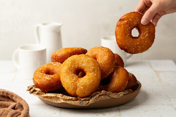 Eating Italian Carnival pastry. Homemade fried yeast raised italian graffe, with a dough made of flour and potatoes. Doughnuts or donuts sugar-coated. Neapolitan cuisine. White background.