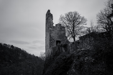 Old stone castle ruins surrounded by trees and hills on a cloudy day in a remote location