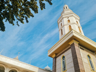 The majestic minaret of Mosque against clear blue sky with some clouds taken from ground. low angle photography.