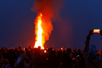 Scenic view of people crowd gathering celebrate traditional big Easter bonfire at twilight night in...