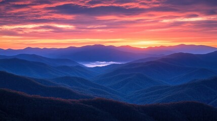 Obraz premium Vibrant sunrise over a vast mountain range, showcasing layers of peaks and valleys bathed in warm, colorful light.