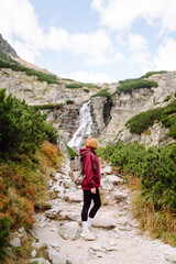 Naklejka premium Woman traveler walking on mountains cliff in summer sunny day under sun light. Adventure active. Tourism