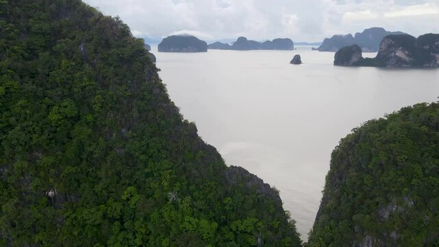 Close up Phang Nga Bay. Rocky islands in the sea with steep slopes overgrown with green trees in the sea bay, the coast is densely overgrown with trees. Top view from a drone. Beauty of marine tropica