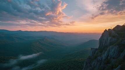 Majestic sunset over a mountain range, showcasing layers of misty valleys and rocky cliffs.