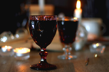 Books, lit candles, red wine, snacks and various deocration on the table. Dark academia or...