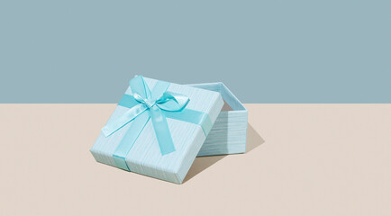Open blue gift box on beige background. Concept of advertising blank mockup or banner for holiday or greeting card.