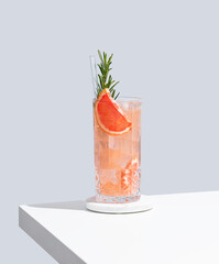 Refreshing cocktail with grapefruit, rosemary and ice in a glass on a blue background with shadow.