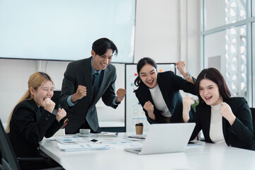 Diverse business team celebrating a successful achievement with excitement and teamwork in a modern office setting.