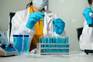 Medical or research scientist or doctor using looking at a test tube of clear solution in a lab or laboratory..