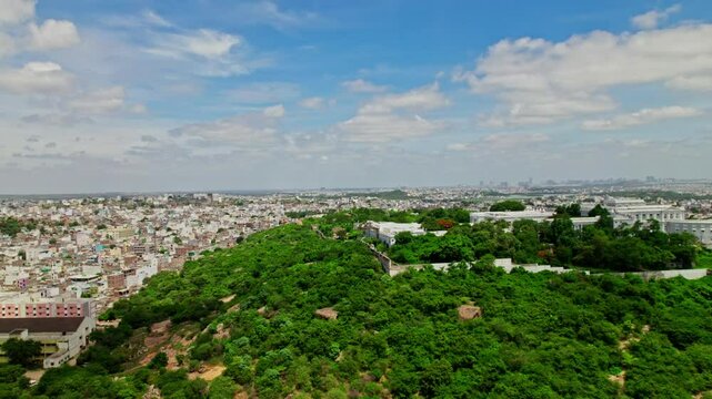 Reval shot of falaknuma palace with trees and crowded residence buildings at engine bowli, falaknuma, hyderabad, telangana, india. day time, push back, drone shot, 4k.
